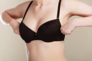 Woman pulls up on her bra before a breast lift with augmentation in Beverly Hills
